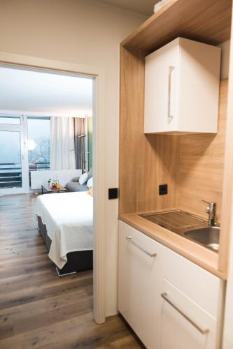 a kitchen with a sink and a bed in a room at Lakeside Lodge mit Seeblick am Kranichsee in Goslar