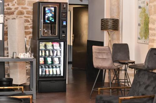 a soda machine with two chairs and a table at Le lieu in Saint-Amour
