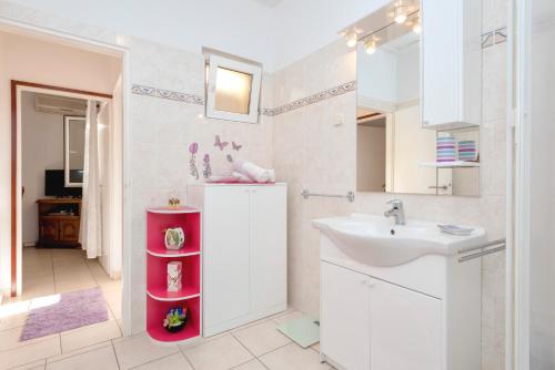 a white bathroom with a sink and a sink at Apartment Oaza in Vrboska