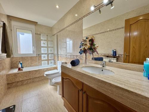 a bathroom with a sink and a toilet with a vase of flowers at Villa Aura en Platja d'Aro in Platja d'Aro