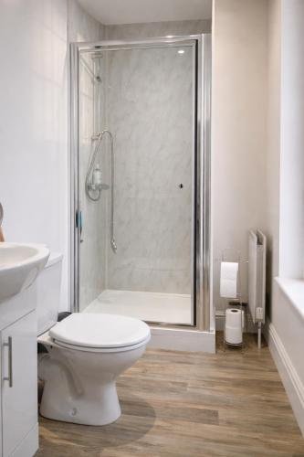 a white bathroom with a shower and a toilet at The Manor House in Peel