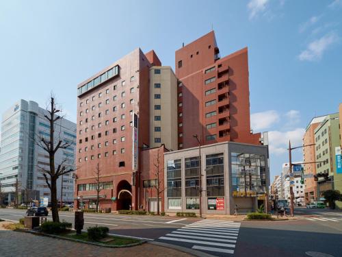 a large building on a city street with a crosswalk at Tabist Hotel Tetora Kitakyushu in Kitakyushu