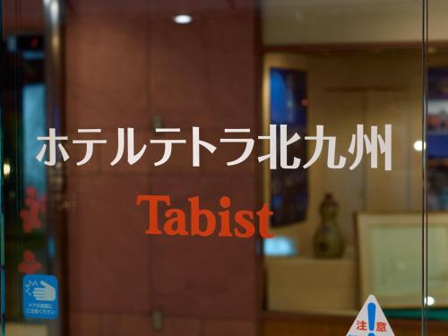 a sign on a glass door in a building at Tabist Hotel Tetora Kitakyushu in Kitakyushu