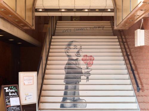 a staircase with a painting of a woman holding apples at Tabist Hotel Tetora Kitakyushu in Kitakyushu