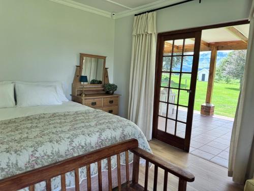 a bedroom with a bed and a sliding glass door at Scafell homestead, Cobham, Himeville in Ixopo