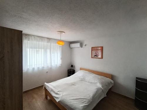 a bedroom with a white bed and a window at Martin apartman in Kruče
