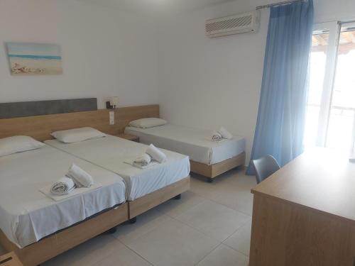 a hotel room with two beds and a window at Karafelas rooms in Skiathos