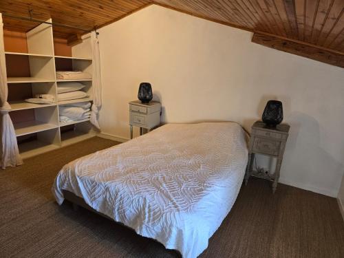 a bedroom with a bed and two nightstands and shelves at La P'tite Chaumiere in Domaize