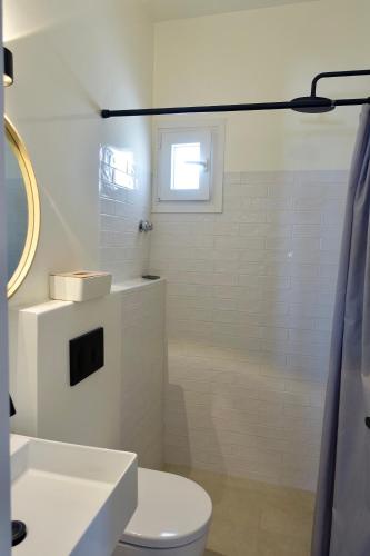 a bathroom with a toilet and a sink and a window at Villa D - Kamari Village in Aliko Beach