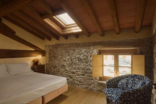 a bedroom with a bed and a chair and a window at Corte dei Mori - Historic Apartments Lazise in Lazise