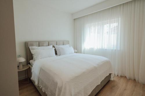 a white bedroom with a large bed and a window at Villa Saint Hill in Međugorje
