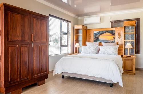a bedroom with a large bed and a wooden cabinet at Sea Spray Self Catering in Duyker Eiland in Britannia Bay