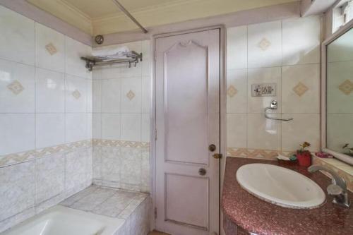 a bathroom with a tub and a sink and a door at Park Palace Hotel in Kolkata