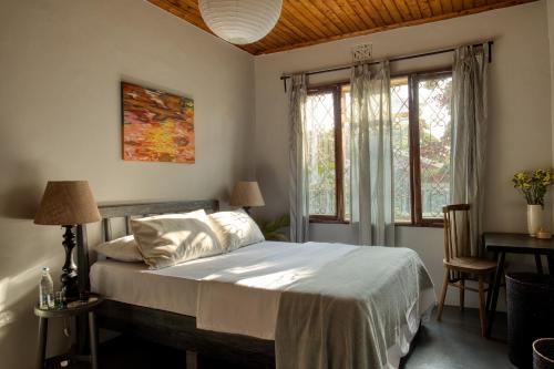 a bedroom with a bed and a table and windows at The Garden Home in Arusha