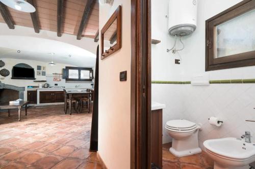 a bathroom with a toilet and a sink and a kitchen at Casa Bados in Dorgali