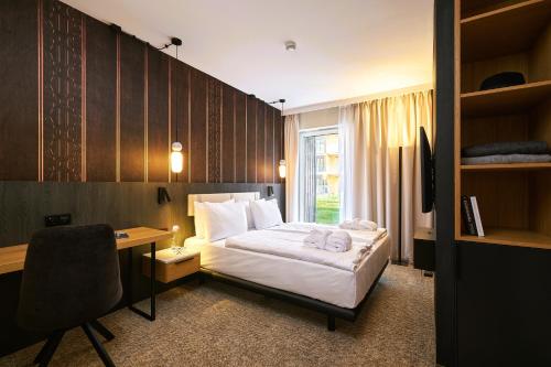 a hotel room with a bed and a desk and a window at Harmony Valley Resort in Szklarska Poręba