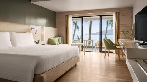 a hotel room with a bed and a view of the ocean at Amari Phuket in Patong Beach