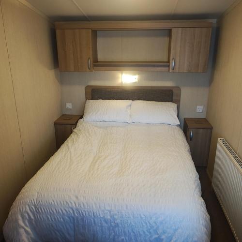 a large bed in a small room with wooden cabinets at Our Retreat By The Waves in Bangor
