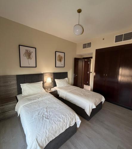 a hotel room with two beds and a lamp at شقة البيلسان فيو Baylasun View in King Abdullah Economic City