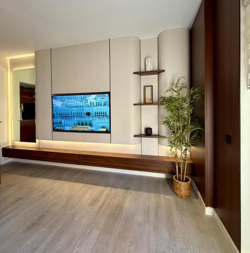a living room with a large television and a plant at شقة البيلسان فيو Baylasun View in King Abdullah Economic City