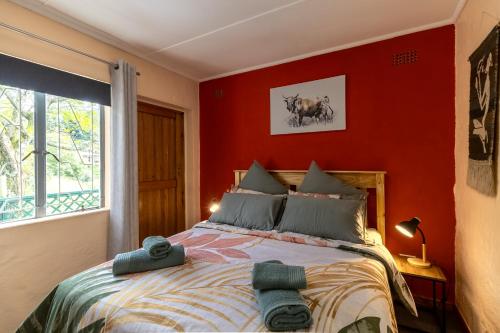 a bedroom with a large bed with a red wall at Birdsong Cottage in Howick
