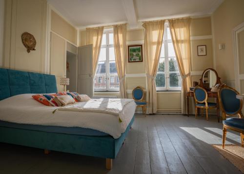 a bedroom with a bed and chairs and windows at Le Palais de la Cathédrale in Saint-Omer
