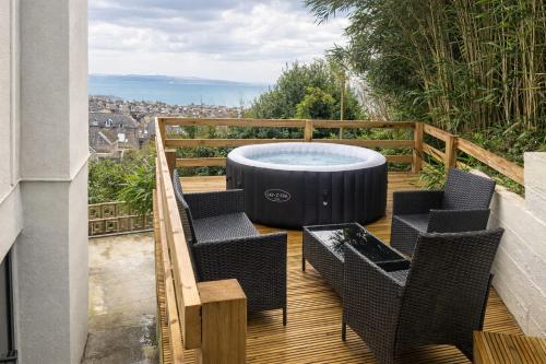 a hot tub sitting on a deck with chairs at Valdermosa in Newlyn
