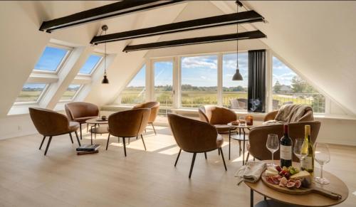 a dining room with chairs and tables and windows at Stor villa til 16 gæster Sauna & vildmarksbad 200 m strand in Børkop