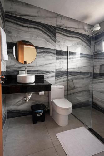 a bathroom with a toilet and a sink and a mirror at Pousada Iraquara in João Pessoa