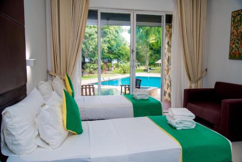 a hotel room with two beds and a pool at Miridiya Lake Resort in Anuradhapura