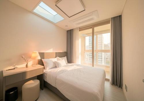 a white bedroom with a bed and a window at Sota Suite Busan Seomyeon in Busan