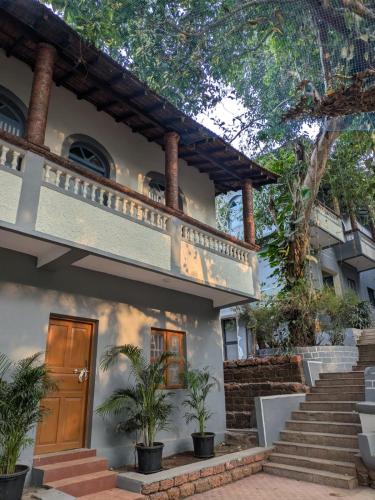 a house with a wooden door and stairs at Artjuna CoLiving in Assagao
