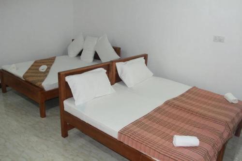 two beds sitting next to each other in a room at Rose Lagoon Hotel in Vakarai