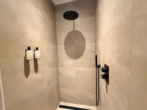 a bathroom with a shower with two soap bottles on the wall at Appartement Ocean Breeze Nes Ameland in Nes