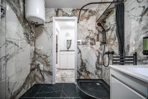 a bathroom with a black tub and marble walls at MVSV Apartment in Kamnik