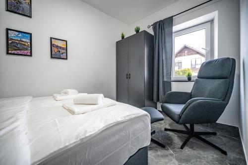 a bedroom with a bed and a chair and a window at MVSV Apartment in Kamnik