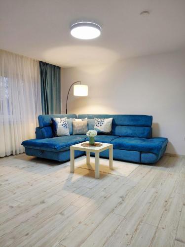 a living room with a blue couch and a table at KM Art Apartman in Sfântu-Gheorghe
