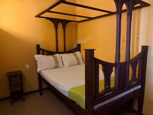 a bedroom with a wooden canopy bed with white pillows at Busara house 2 in Zanzibar City