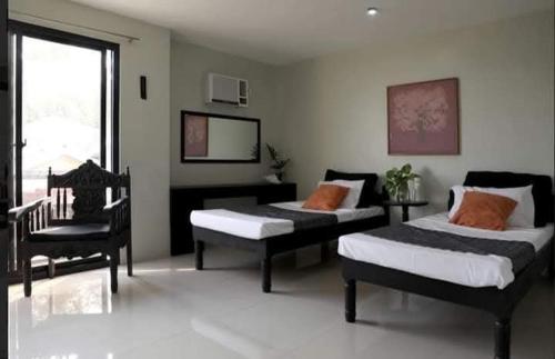 a bedroom with two beds and a chair and a mirror at SanRosa Boutique Hotel BnB in Bulalakao