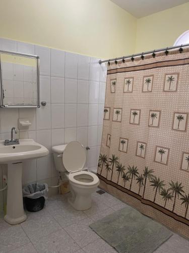 a bathroom with a toilet and a shower curtain with palm trees at Privat 3 bedroom apartment in Sosua