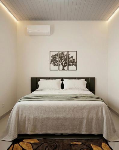 a bedroom with a large bed with two pictures on the wall at Apartamento Aconchego II in Alta Floresta
