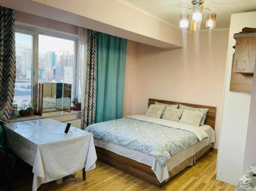 una camera da letto con un letto con un tavolo e una finestra di Sky apartment-2 a Ulaanbaatar