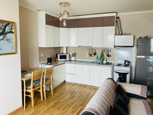 una cucina con mobili bianchi, un tavolo e un frigorifero di Sky apartment-2 a Ulaanbaatar