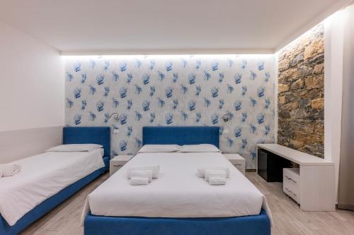 two beds in a room with blue and white wallpaper at 5 Terre Lodge in La Spezia
