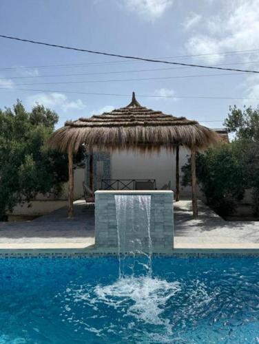 a water fountain in front of a straw hut at Djerba 7 in Aghīr