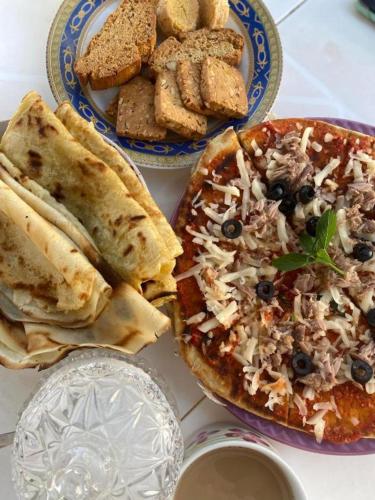 a table with two plates of food and a pizza at Djerba 7 in Aghīr
