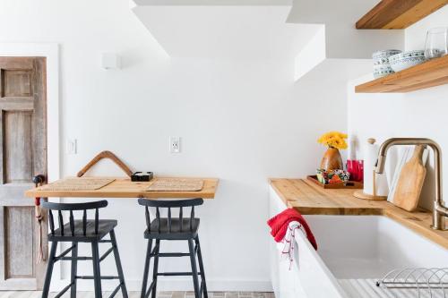 a kitchen with a sink and two bar stools at The Forest Door - Studio Suite in Stone Cottage in Tryon