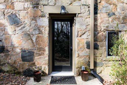 a stone building with a black door and a window at The Forest Door - Studio Suite in Stone Cottage in Tryon