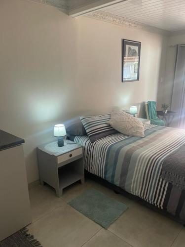 a bedroom with a bed and a table with a lamp at Shady Seringa Accommodation in Vanderbijlpark
