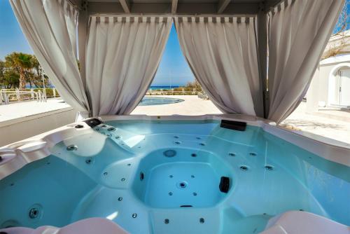 a hot tub in a room with a view of the beach at Anemos Luxury Grand Resort in Georgioupolis